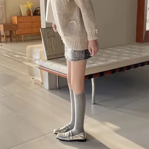 Detailed shot of comfortable grey knee high socks paired with stylish silver shoes for women.