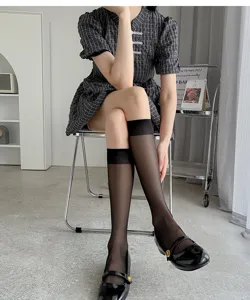 Vue détaillée de chaussettes hautes noires ultra-minces et transparentes en intérieur.