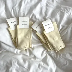 Cozy cotton mid-calf women socks in soft yellow color with simple tags for daily wear.