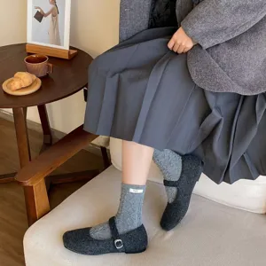 Detailaufnahme gemütlicher grauer Wollstrick-Socken mit kleinem Marken-Etikett.