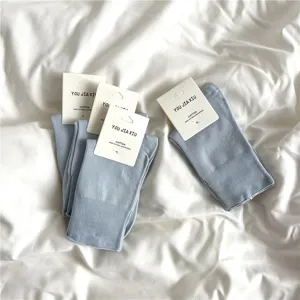 Closeup view of light blue cotton mid-tube women socks with paper tags on white fabric background