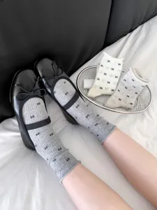 Detailed view of women crew socks featuring cute bow patterns, paired with black shoes.