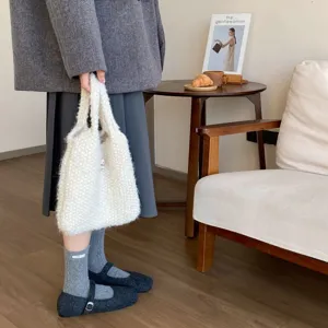 Detailaufnahme von dicken kuscheligen Wollmisch-Stulpensocken mit süßem Etikett im Winter.