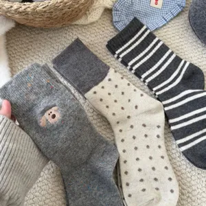 Primo piano di calzini invernali in lana da donna con ricamo di cagnolino, pois e righe.