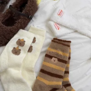 Cute capybara embroidered fluffy socks and warm winter footwear detail flat lay view close up