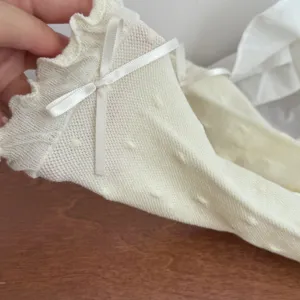 Close-up detail of women cream mid-calf socks featuring ruffle lettuce edge and sweet bow.