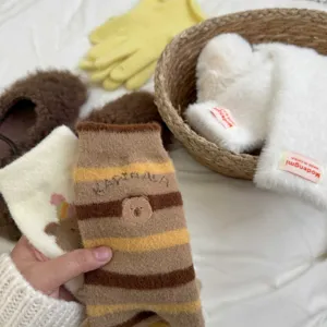 Close-up of cute capybara embroidered fuzzy mid-tube socks with cozy striped design for winter warmth.