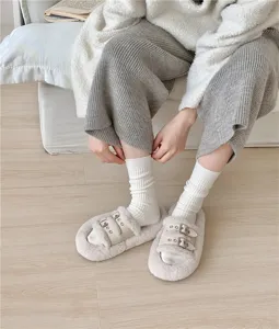 Detail shot of white ribbed slouch socks worn by a model in a cozy indoor setting.