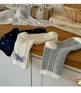 Primo piano dei dettagli di calze in maglia stile coreano con fiocchi e motivi autunnali.