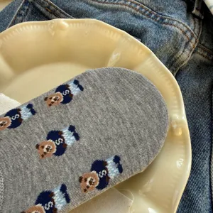Grey cotton women's short sock detail, cute bear knit pattern texture close-up view.