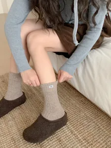 Detailed view of women's warm wool knit mid-tube socks with cute brand label design.