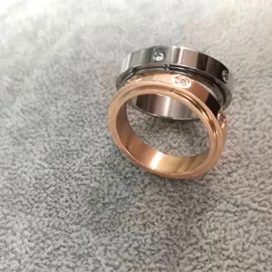 Roestvrijstalen paar ringen met zirkonia en roterend ontwerp in zilver en roségoud.