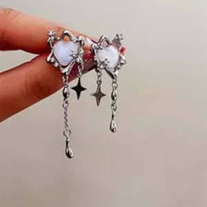 Primo piano di orecchini asimmetrici con cuore e nappina a stella, gioielli stile cool.
