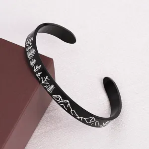 Brazalete rígido negro de acero inoxidable con grabado láser de montañas y bosque de pinos.