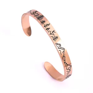 Brazalete rígido de acero inoxidable en oro rosa con grabado de paisaje de montaña y pinos.