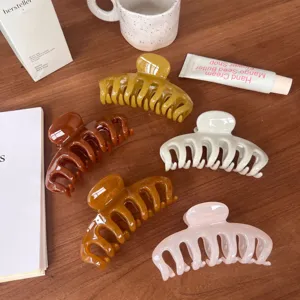Detail view of large hollow hair claw clips in various stylish colors, displayed on a wooden table.