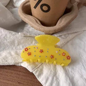 Nahaufnahme Detail der transparenten gelben Harz Haarklammer mit bunten Strasssteinen und Blumen.
