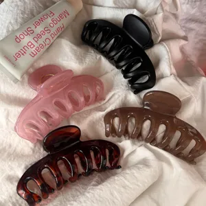 Detailed close-up of large hair claw clips in assorted colors on a soft white fabric surface.