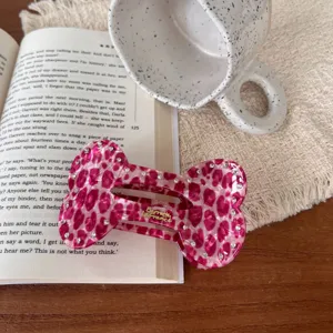 Nahaufnahme der rosa Strass Knochen Haarklammer stilvoll mit Buch und Keramik Tasse.