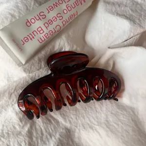Close-up detail of dark brown hair claw clip, hollow design, elegant minimalist hair accessory.
