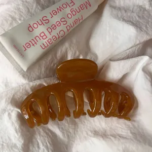 Detailed view of large amber acrylic hair claw clip showcasing hollow design and glossy texture.