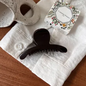 Vue détaillée d'une pince à cheveux marron chic sur lin, accessoire élégant de style français.