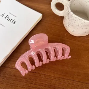Pink translucent hair claw clip detail shot, elegant hollow design for daily styling.