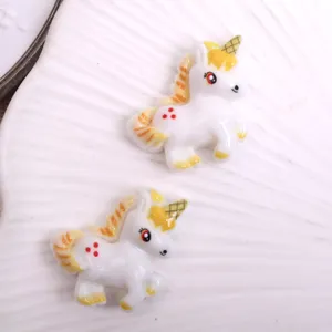 Resin unicorn charm detail view, showing cute white pegasus flatback design with yellow mane.