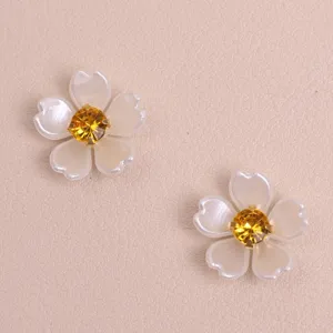 Close-up detail of white pearl five-petal flower DIY patch with a sparkling yellow rhinestone.
