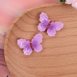 Detailed view of glossy purple gradient butterfly resin flatbacks for DIY phone cases and bows.