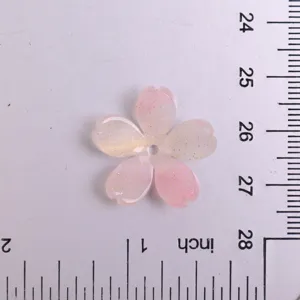 Primo piano dettagliato del ciondolo in resina a forma di fiore di ciliegio rosa glitterato.