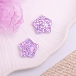 Close-up of cute purple glitter star resin cabochons for DIY hair accessories and crafts.