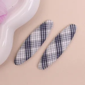 Close-up detail view of black and white plaid oval hair clips and DIY fabric items.
