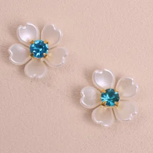 Close up detail of white pearl five petal flower patch with blue crystal center for DIY crafts.