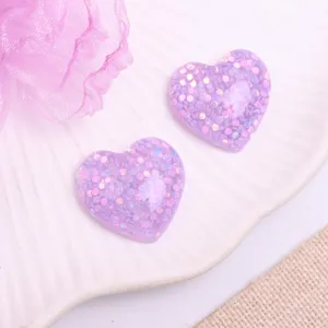Close up of purple glitter heart resin cabochons for DIY hair accessories and crafts.