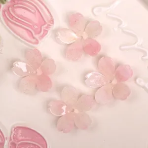Primo piano dettagliato ciondoli in acetato rosa a cinque petali con delicati glitter oro per fai da te.
