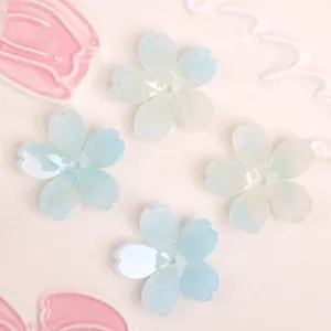 Primo piano dettagliato di ciondoli fai-da-te a fiore a 5 petali glitterati azzurri chiari.