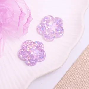 Close-up view of purple glitter flower resin charms for DIY hair accessories and crafts.