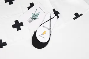 Primo piano di fantasmini neri con cinturino su cartone bianco, design estivo pulito.