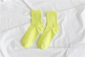 Close-up detail of fluorescent yellow crew socks, showing smooth cotton texture and knit cuff.
