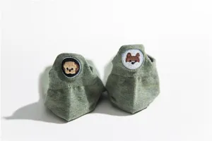 Close-up detail of cute dog embroidery on the heel of green cotton boat socks for women.