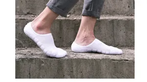 Gros plan de chaussettes de sport invisibles blanches basses sur des marches en béton.
