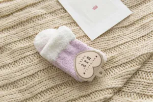 Close-up detail of fluffy coral fleece winter thermal sleep socks in soft pink and white color.