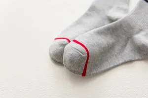 Close-up detail of grey women socks with red toe stripe, soft cotton texture, minimalist style.