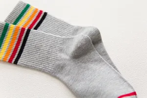 Close-up detail of women's grey mid-calf socks featuring colorful striped cuffs.