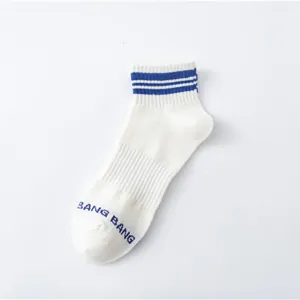 Detailansicht weißer niedriger Sportsocken mit blauen Streifen und gesticktem Text.