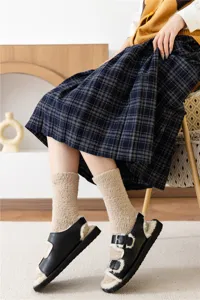 Detail shot of cozy coral fleece mid-calf socks worn with plush-lined black sandals.
