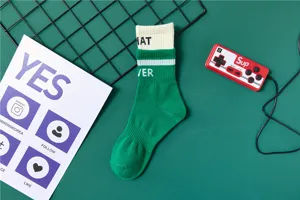 Detailaufnahme von gruen-weissen Baumwoll-Mittel-Socken mit gestrickten Buchstaben, casual.