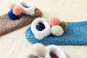 Dettaglio calzini invernali soffici, calze da casa in morbido peluche con pon pon carini.
