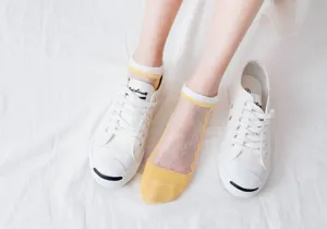 Calzini corti trasparenti in seta di vetro con design a rete traspirante nei colori giallo e bianco.